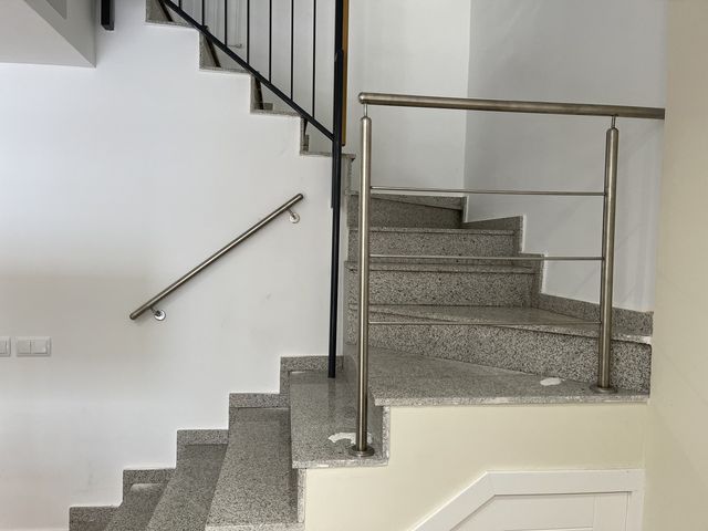 Barandilla metálica y pasamanos con panel de vidrio en escalera