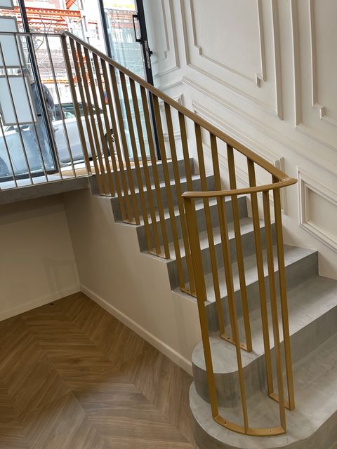 Barandilla metálica en acabado dorado en escalera interior