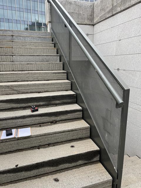 Barandilla metálica con panel perforado en escalera exterior
