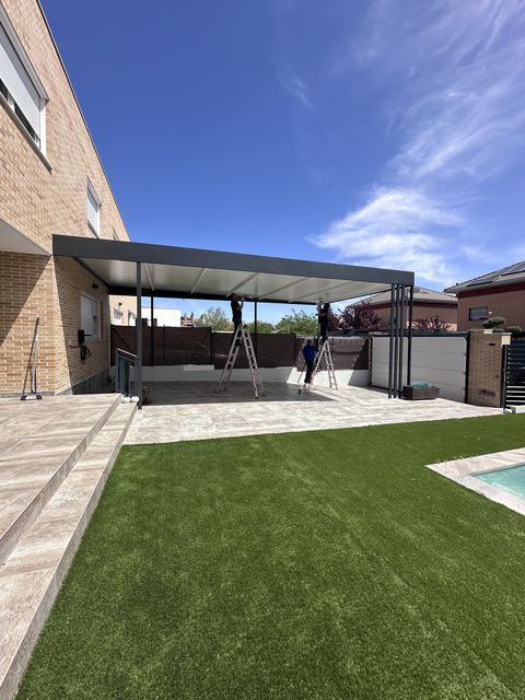 Pérgola metálica de gran tamaño sobre patio con césped