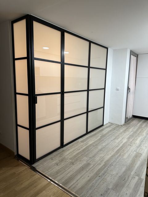 Puerta metálica con perfilería negra y cristal esmerilado