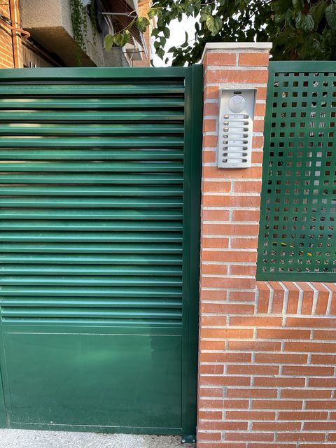 Puerta metálica de acceso junto a portero automático