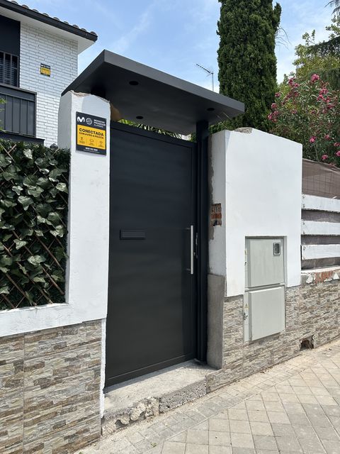 Puerta metálica peatonal de acceso a vivienda con visera