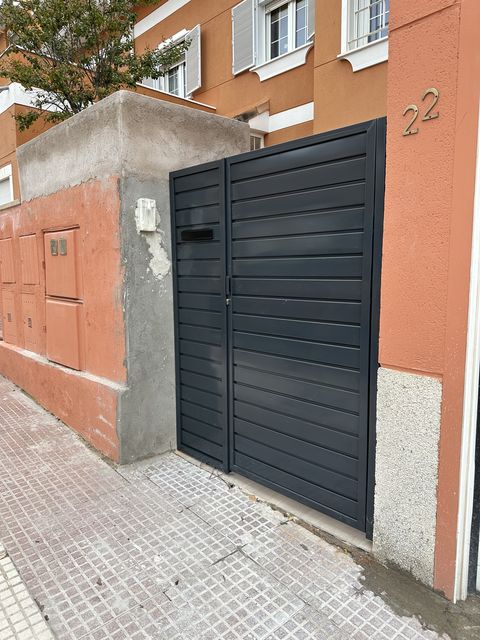 Puerta metálica peatonal de lamas horizontales en acceso a vivienda