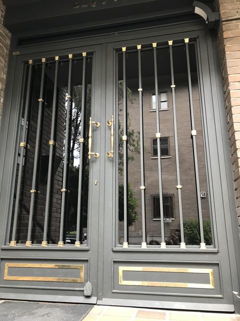 Puerta de portal metálica ornamental con detalles dorados