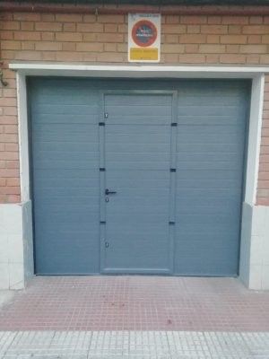 Puerta de garaje seccional gris con puerta peatonal integrada