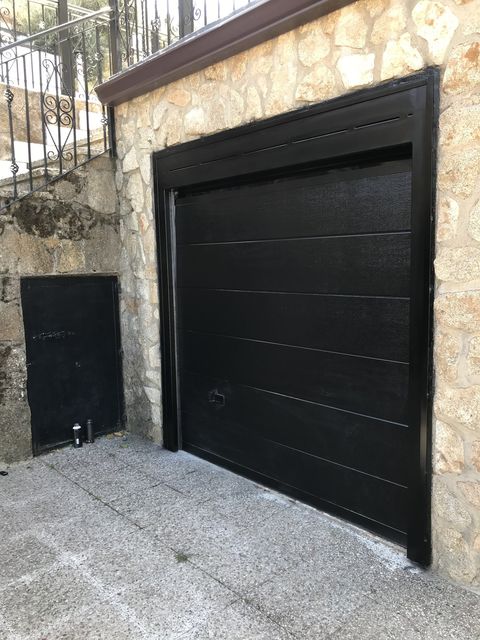 Puerta de garaje metálica seccional junto a trampilla de registro